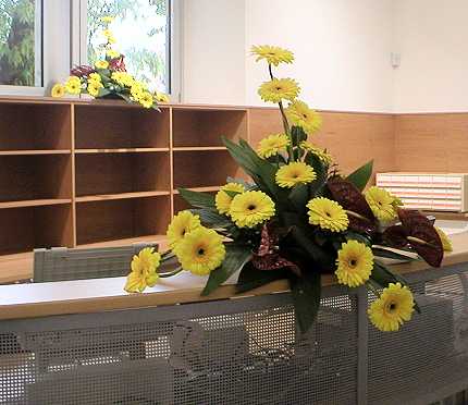 Desk, pult ili kako god ve�, bio je jo� uvijek prazan ali ukra�en prekrasnim �utim cvjetnim aran�manima. 